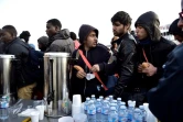 Des migrants reçoivent de la nourriture et des boissons pendant l'évacuation de leur campement illicite Porte de la Chapelle à Paris, le 9 mai 2017
