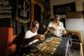 L'Egyptien Ahmed Othmane supervise la broderie d'une épaisse étoffe noire de versets coraniques avec des fils d'or, le 15 juin 2022, au Caire