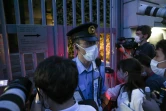 Un policier en faction tente de contenir les journalistes, le 2 août 2021, devant l'ambassade de Pologne à Tokyo où s'est réfugiée Krystsina Tsimanouskaya