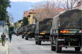 Des camions de l'armée italienne transportent des cercueils à travers la ville de Bergame, depuis le cimetière de la ville jusqu'à des crematoriums d'autres villes italiennes, le 26 mars 2020