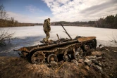 Un militaire ukrainien se tient près d'un tank russe détruit dans la ville de Trostyanets en Ukraine le 29 mars 2022