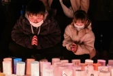 Des enfants prient lors d'une cérémonie matinale à la mémoire des victimes à l'occasion du 30e anniversaire du tremblement de terre de Kobe, le 17 janvier 2025 au Japon