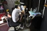 Brandon Burgos, 11 ans, réalise un tatouage sur un client, le 10 novembre 2021 à Puebla, au Mexique