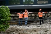 Des employés SNCF travaillent à côté d'un TGV reliant Toulouse à Bordeaux dont les ballasts situés sous la voie ferrée ont été emportés par le débordement d'un ruisseau en raison des intempéries, le 20 mai 2025, à Tonneins, dans le Lot-et-Garonne
