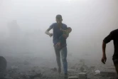Un Syrien portant un enfant apparaît dans un nuage de poussière crée par des bombardements sur un quartier rebelle dans la banlieue de Damas, le 30 septembre 2016