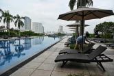 Une employée nettoie les transats devant la piscine de l'hôtel Chatrium Riverside de Bangkok, le 19 octobre 2021
