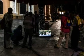 Des passants regardent la télévision dans la rue, place Bolivar, le 13 décembre 2019 à Caracas, au Venezuela