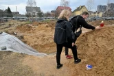 Un homme allume une bougie sur une fosse communie près de Kiev le 9 avril 2022