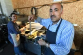 Jawad (g) et Zainab Al-Khajee, couple de journalistes irakiens réfugiés en France, préparent des plats irakiens, le 23 juin 2018 dans le snack de Darwin, un espace associatif sur les bords de la Garonne, à Bordeaux