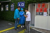 Un travailleur sanitaire aide des habitants de Shanghai à obtenir un QR code leur permettant de se faire dépister contre le Covid-19, le 14 mars 2022