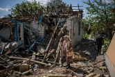 Un couple sort des valises depuis leur maison détruite à Vilkhivka, près de Kharkiv, est de l'Ukraine, le 14 mai 2022
