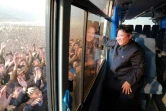 Photo diffusée par l'agence officielle nord-coréenne Korean Central News Agency (KCNA) le 8 octobre 2015 montrant le dirigeant Kim Jong-Un saluant la foule depuis un autobus pendant qu'il inspecte un nouveau village Paekhak-dong dans le district de Sonbong