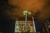 Des membres de "la nouvelle bande de la terrasse" projettent un slogan sur le mur d'un immeuble, le 9 août 2020 à Medellin, en Colombie