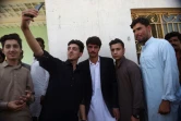 Séance de selfie avec Arshad Khan (c), marchand de thé pakistanais devenu phénomène sur le web, le 19 octobre 2016 à Islamabad