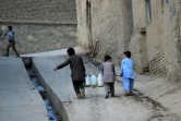 Des enfants transportent des bidons d'eau dans une rue de Kaboul, le 25 octobre 2018 en Afghanistan