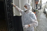 Un employé désinfecte l'entrée d'un immeuble pendant l'épidémie de coronavirus, le 20 mars 2020 à Alger