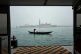 Un gondolier manoeuvre sa gondole vide sur le bassin de Saint-Marc, avec l'église San Giorgio maggiore en arrière-plan, le 6 février 2021 à Venise (Italie)
