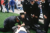 Des policiers aident un supporteur blessé dans le stade de Hillsborough, le 15 avril 1989 à Sheffield, au Royaume-Uni
