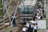 Des passagers d'un train marchent sur les rails après une interruption du trafic ferroviaire due à un fort séisme à Osaka au Japon, le 18 juin 2018