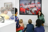 Des enfants observent avec une médiatrice l'oeuvre de la photographe américaine Sandy Skoglund "Fox Games" lors de l'exposition "La Caravane du Bizarre" du musée mobile du Centre Pompidou installé à Verdun, dans la Meuse, le 3 janvier 2024