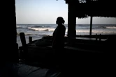 Une commerçante regarde l'océan depuis son petit commerce sur la plage d'El Zonte, au Salvador, le 23 juillet 2024