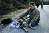 Un kurde syrien secourt sa mère qui vient de s'évanouir de fatigue sur l'ile de Lesbos le 16 octobre 2015 où ils viennent d'arriver en provenance de Turquie