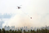 Un hélicoptère bombardier d'eau survole un massif forestier en feu à Korskrogen, en Suède, le 25 juillet 2018.