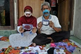 Dwi Rahayu (g) et son mari Elfiandi, tous deux sourds et muets, présentent leurs masques transparents à Yogyakarta, en Indonésie, le 22 avril 2020