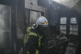 Un pompier éteint une maison en feu touchée par des roquettes russes dans le quartier Shevchenkivsky de Kiev, en Ukraine, le 23 mars 2022