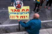 Un homme assis avec une pancarte anti-Netanyahou lors d'une manifestation à Tel Aviv