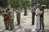 Des couples de militaires ukrainiens, Kristina et Vitali Orlich (à droite), ainsi que Kristina Liouta et Volodymyr Mikhalchouk (à gauche), s'embrassent après avoir été mariés dans la ville de Droujkivka, dans l'est de l'Ukraine, le 12 juin 2022