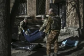 Des militaires ukrainiens emmènent un cadavre dans les environs de l'Académie nationale des sciences, touchée par une frappe, à Kiev, le 22 mars 2022