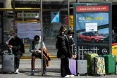 Des touristes portant des masques attendent le bus pour l'aéroport, à Barcelone (Espagne) le 15 mars 2020