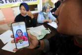 Un proche d'une victime du tsunami indonésien montre une photo à un responsable, dans le centre d'identification d'un hôpital à Pandeglang (province de Banten), le 25 décembre 2018