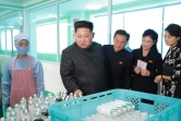 Photo du 29 octobre 2017 de l'agence de presse Nord coréenne (KCNA) montrant le leader nord-Coréen Kim Jong-Un (2eG) dans usine avec sa femme Ri Sol-Ju (D)