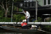 Nopadol, postier, distribue des lettres et colis aux habitants vivant sur les bords d'un canal dans la province de Bang Khun Thian, près de Bangkok en Thaïlande, le 17 juillet 2017