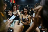 Des participantes à un cours d'apprentissage à prendre la pose vérifient leurs photos sur leur téléphone portable, dans un studio à Hanoï le 2 mars 2021 
