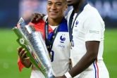 L'attaquant français Kylian Mbappé (g) et le milieu de terrain français Paul Pogba posent avec le trophée à la fin de la finale de la Ligue des Nations de football entre l'Espagne et la France au stade San Siro de Milan, le 10 octobre 2021.
