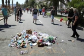 Des passants jettent le 18 juillet 2016 des détritus à l'endroit où aurait été tué Mohamed Des passants jettent le 18 juillet 2016 des détritus à l'endroit où a été tué Mohamed Lahouaiej-Bouhlel, près de l'inscription "Lâche!" sur le bitume