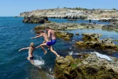Des adolescents sautent d'un rocher dans la mer, le 16 juillet 2022 à Sébastopol, en Crimée
