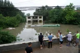 Des personnes regardent un bâtiment partiellement submergé dans une zone inondée, après de fortes pluies dans le district de Fangshan à Pékin, le 31 juillet 2023
