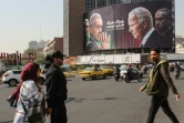 Des Iraniens passent à Téhéran devant un panneau affichant d'un côté les photos du président iranien Massoud Pezeshkian (2 G) avec le chef d'état-major, Mohammad Bagheri (G), et de l'autre celle du président américain Joe Biden (2 D) avec le  Premier ministre israélien Benjamin Netanyahu (D), le 27 octobre 2024