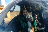 Une jeune déplacée syrienne tient son chat à l'intérieur d'une voiture avant de partir pour un complexe résidentiel, construit près de la ville d'al-Bab, le 9 février 2022 en Syrie 