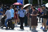 Un policier chinois écarte des badauds rassemblés devant l'ambassade des Etats-Unis après une explosion, le 26 juillet 2018 à Pékin
