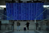 Photo prise le 16 septembre 2022 montrant des voyageurs cherchant des informations sur leur vol à l'aéroport Roissy-Charles de Gaulle