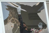 Un policier israélien nettoie du verre brisé après une explosion provoquée par une attaque de drone, à Tel-Aviv le 19 juillet 2024