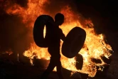 Un Palestinien brûle des pneus dans le village de Beita en Cisjordanie occupée, face à une colonie israélienne, le 13 juin 2021 