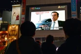 Des passants regardent le 22 novembre 2018 à Tokyo la photo de Carlos Ghosn, patron de Renault-Nissan, arrêté pour soupçons de malversations financières et fraude fiscale