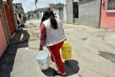 Une femme porte des sceaux remplis d'eau à Mexico, le 19 avril 2017