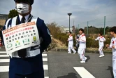 Azusa Iwashimizu (centre D), membre de l'équipe nationale féminine de football du Japon, porte la flamme olympique lors de la première journée du relais à Naraha (Japon) le 25 mars 2021 